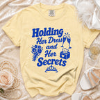 Yellow t-shirt with blue text "Holding Her Dress and Her Secrets".