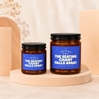 Two amber glass candles with blue labels reading "The Seating Chart Falls Apart".