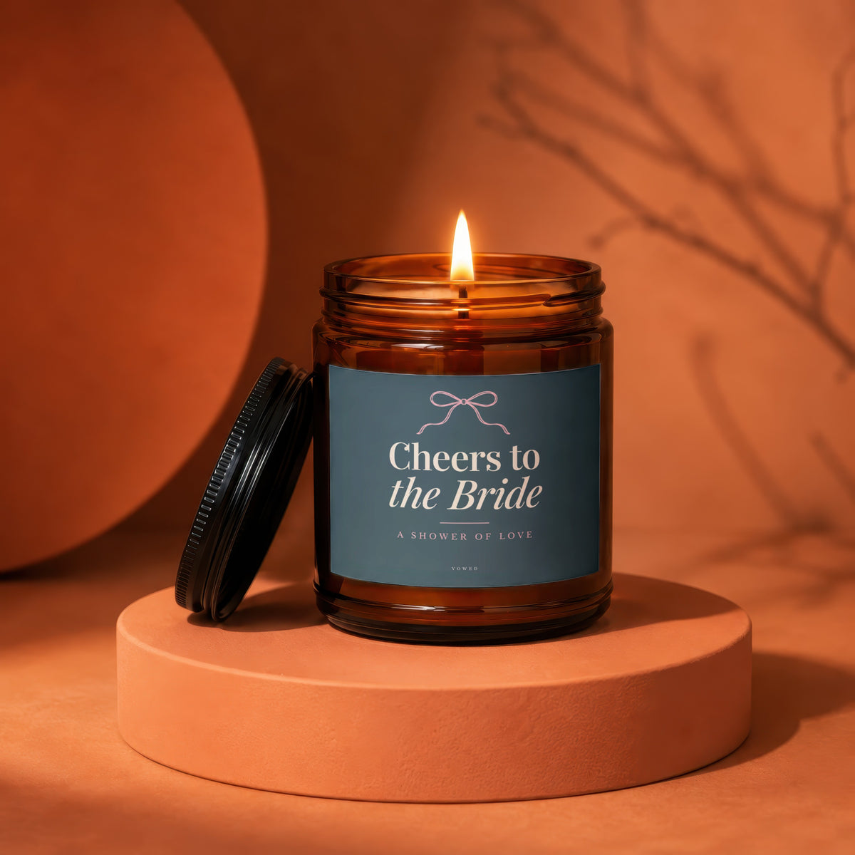 Amber jar candle with lit flame, reads "Cheers to the Bride".