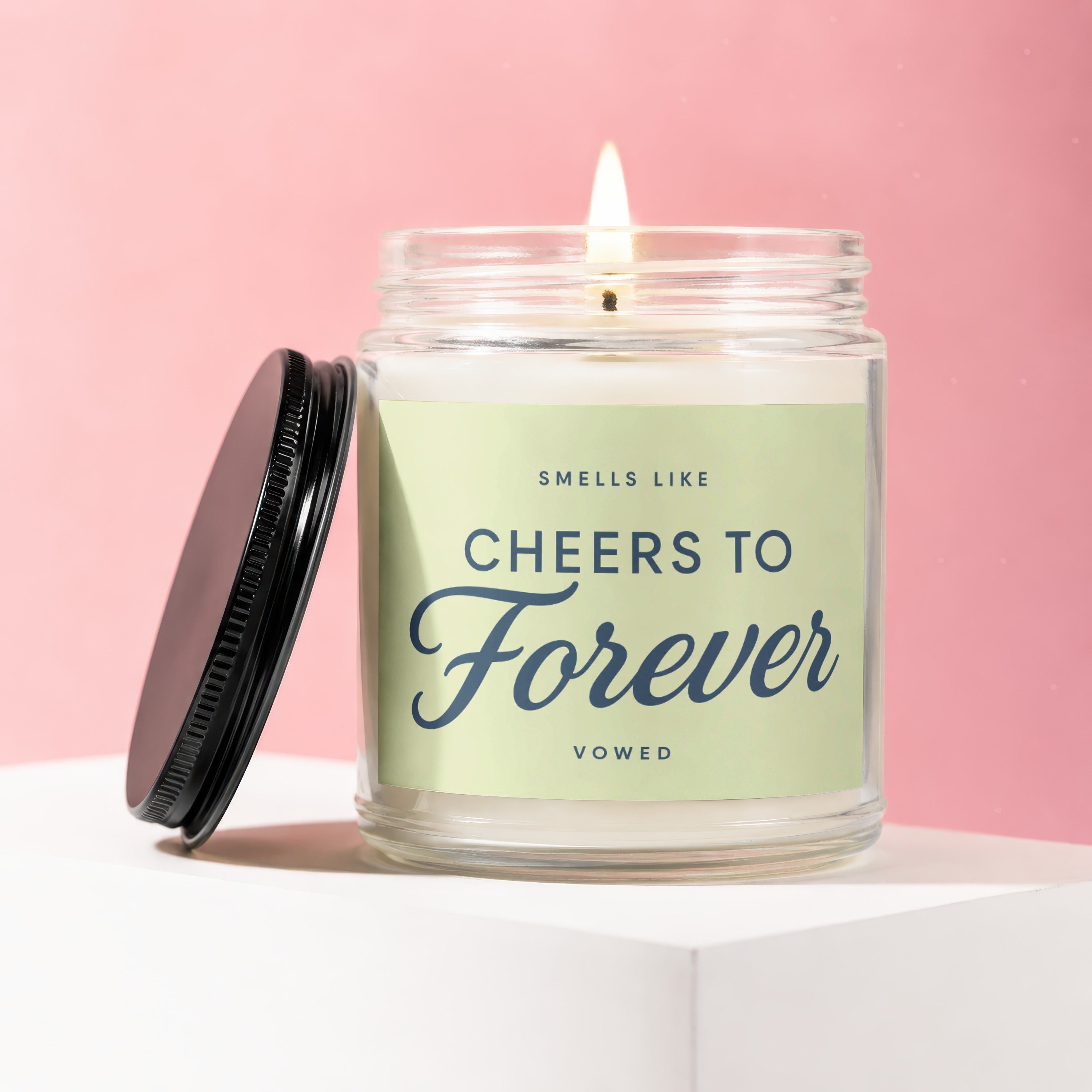 Lit candle in glass jar with label that reads "SMELLS LIKE CHEERS TO Forever VOWED".