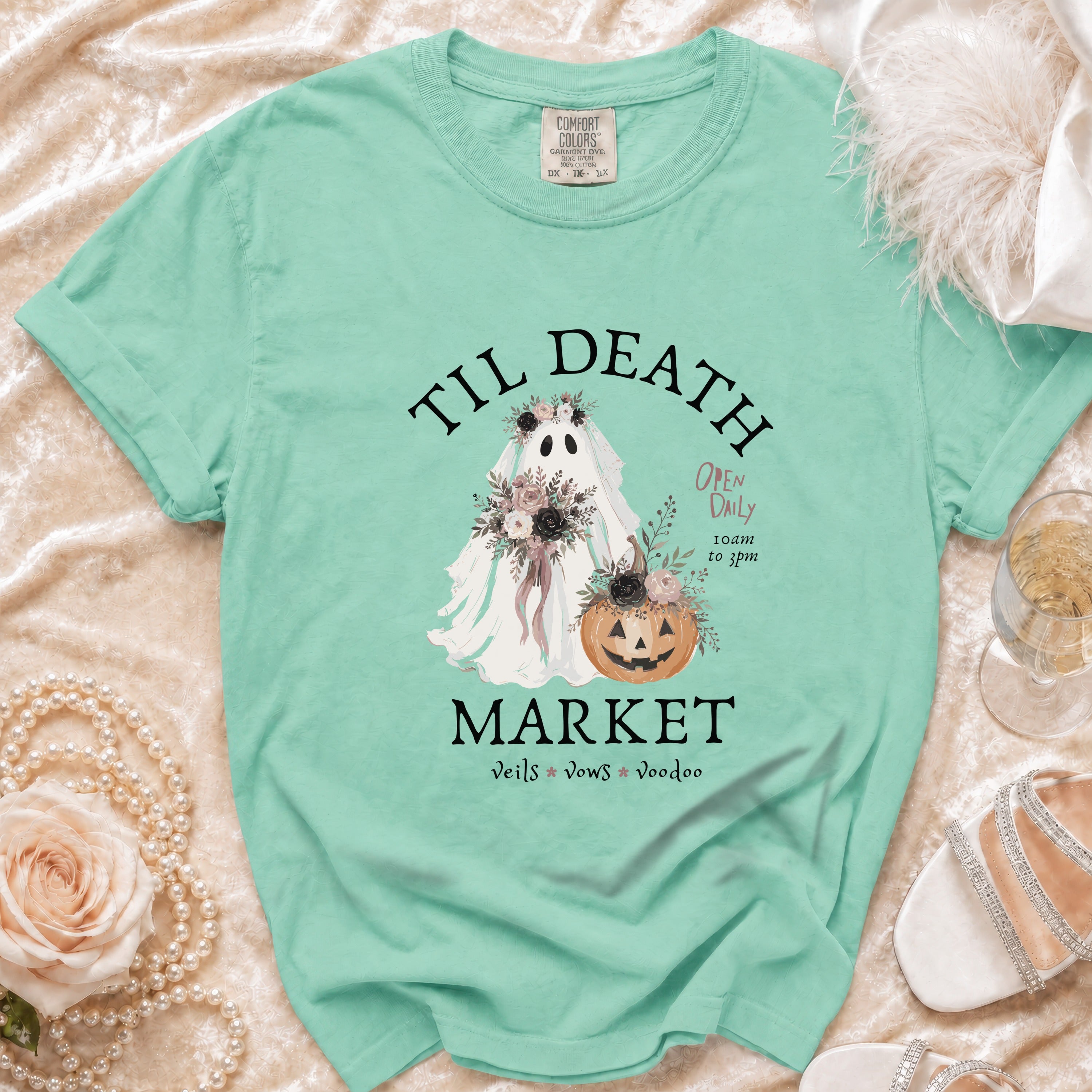 Teal t-shirt with a ghost wearing flowers and a pumpkin, reading "Til Death Market".