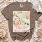 Brown t-shirt with a graphic of a margarita and text saying "THIS GIRL NEEDS A MARGARITA".