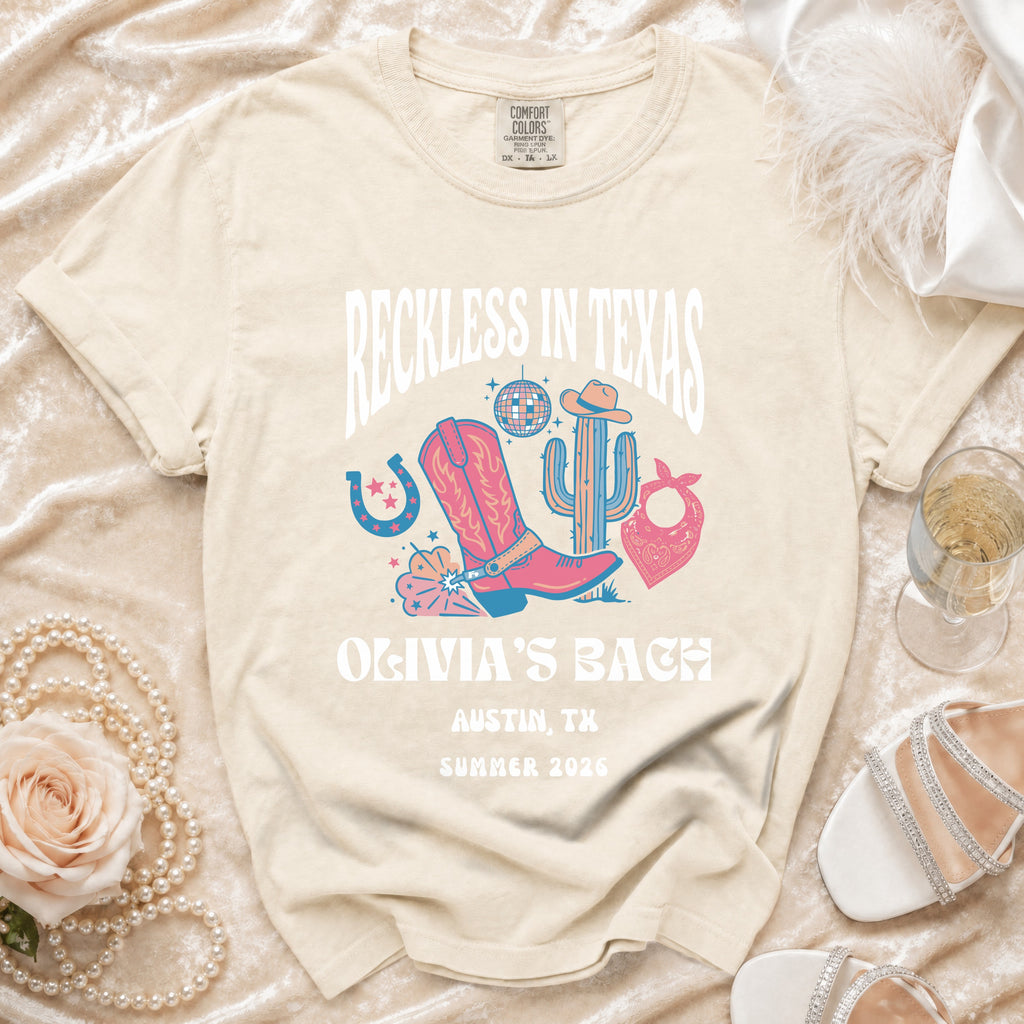 Cream t-shirt with "Reckless in Texas" graphic for Olivia's Bach, Austin, TX, Summer 2026.