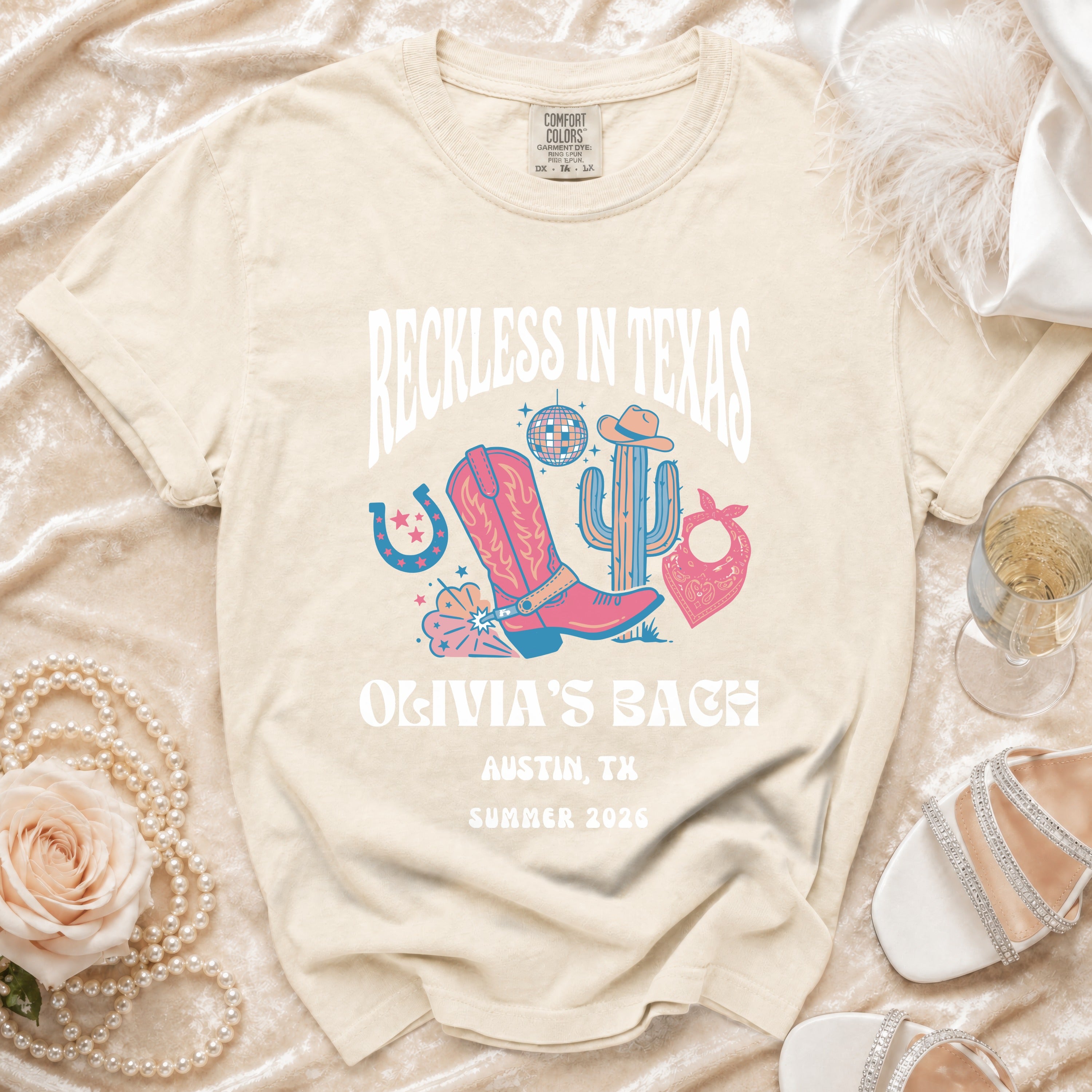Cream t-shirt with "Reckless in Texas" graphic for Olivia's Bach, Austin, TX, Summer 2026.