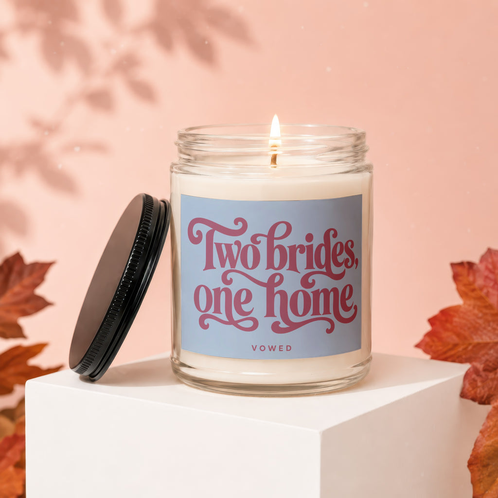 Candle with text "Two brides, one home VOWED" on a pink background.