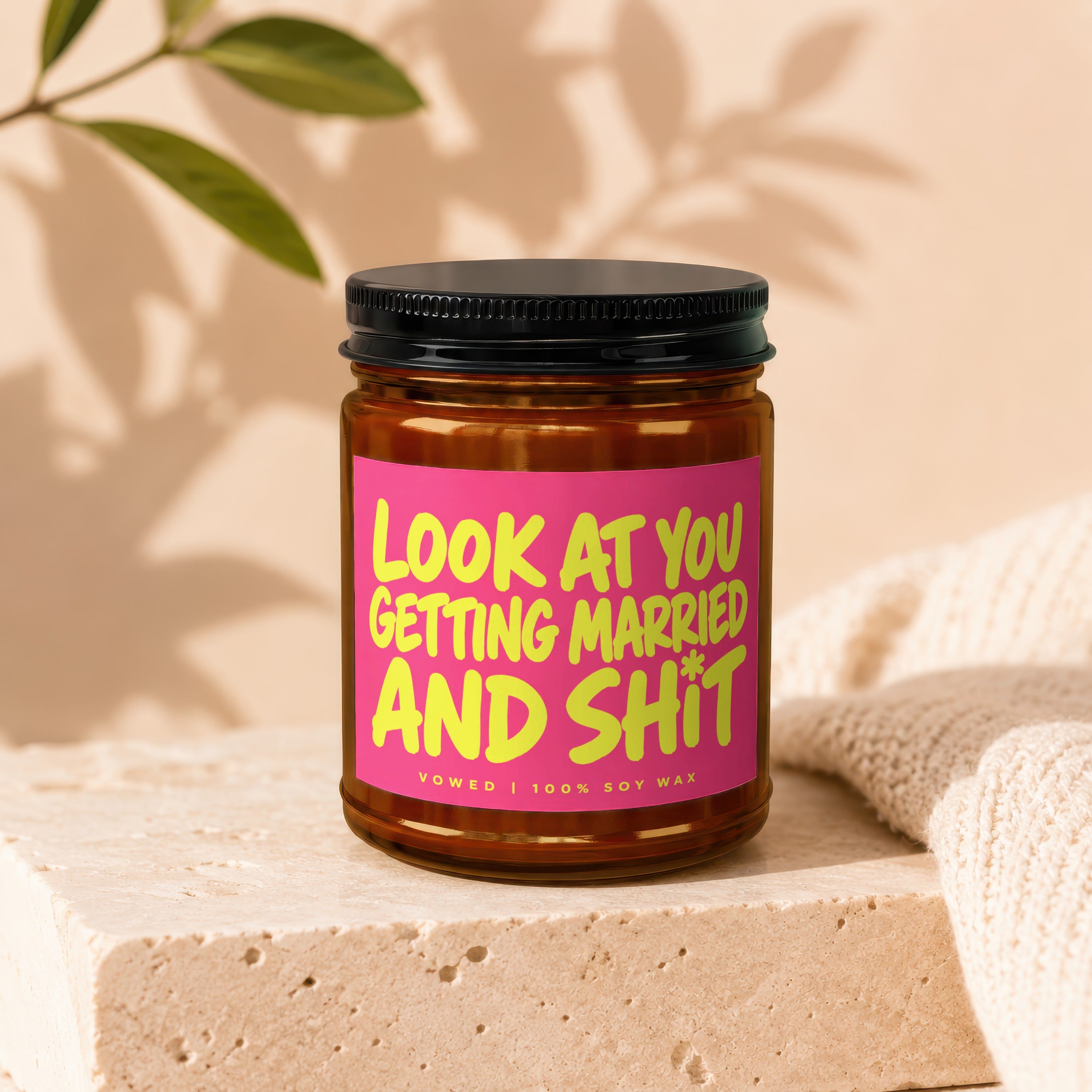 Amber jar candle with pink label text "LOOK AT YOU GETTING MARRIED AND SH*T VOWED | 100% SOY WAX".