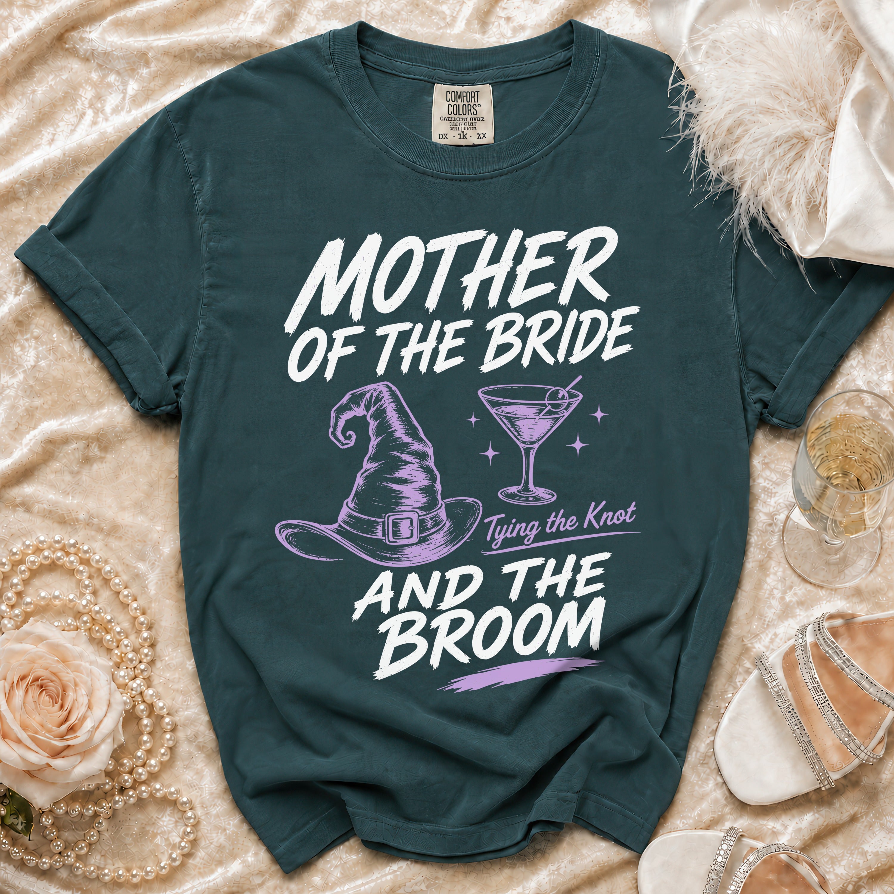 Teal t-shirt with "Mother of the Bride and the Broom" text, witch hat, and cocktail.