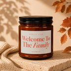 Amber jar candle with "Welcome To The Family" text, sits on stone.