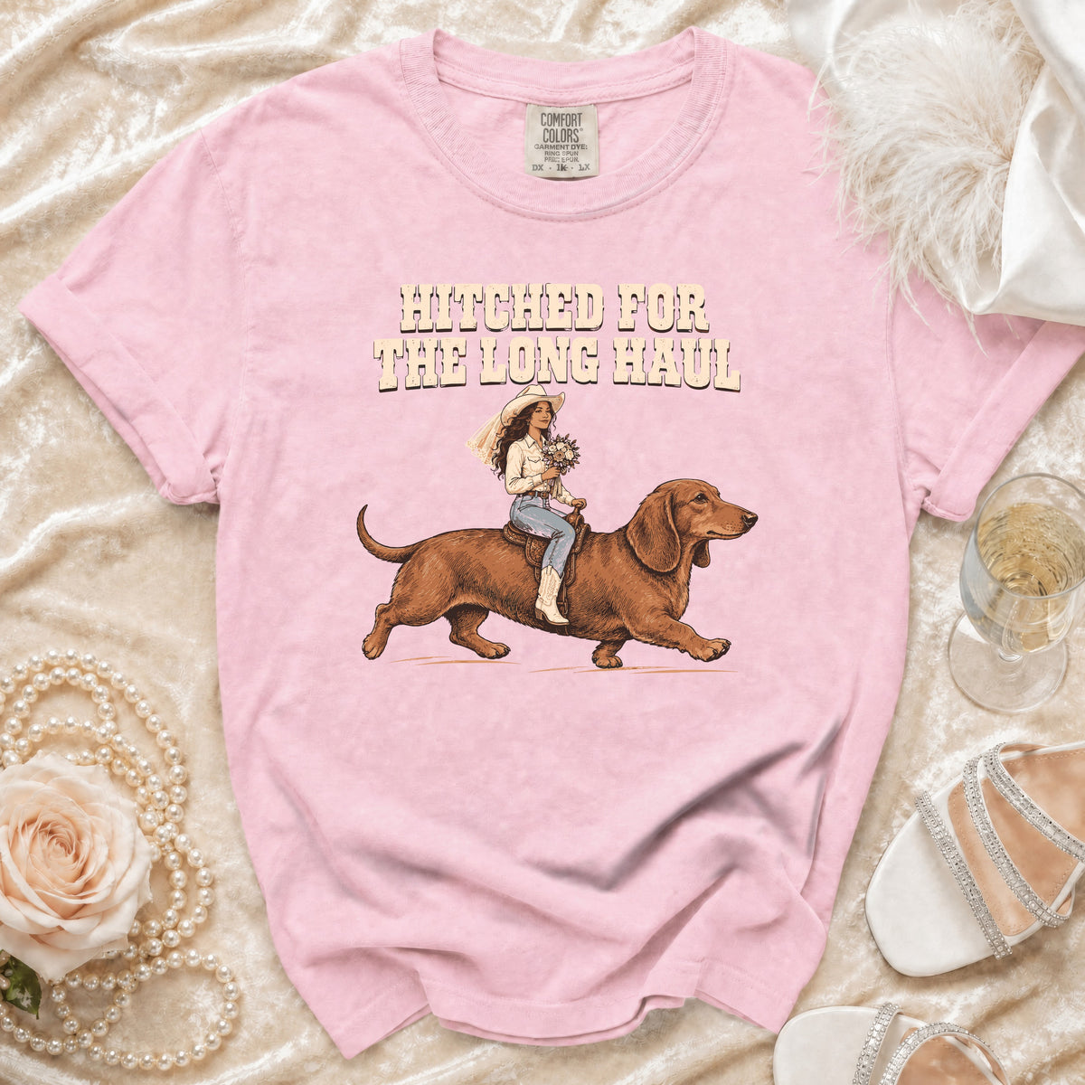Pink t-shirt with "Hitched for the Long Haul" text and graphic of bride riding dachshund.