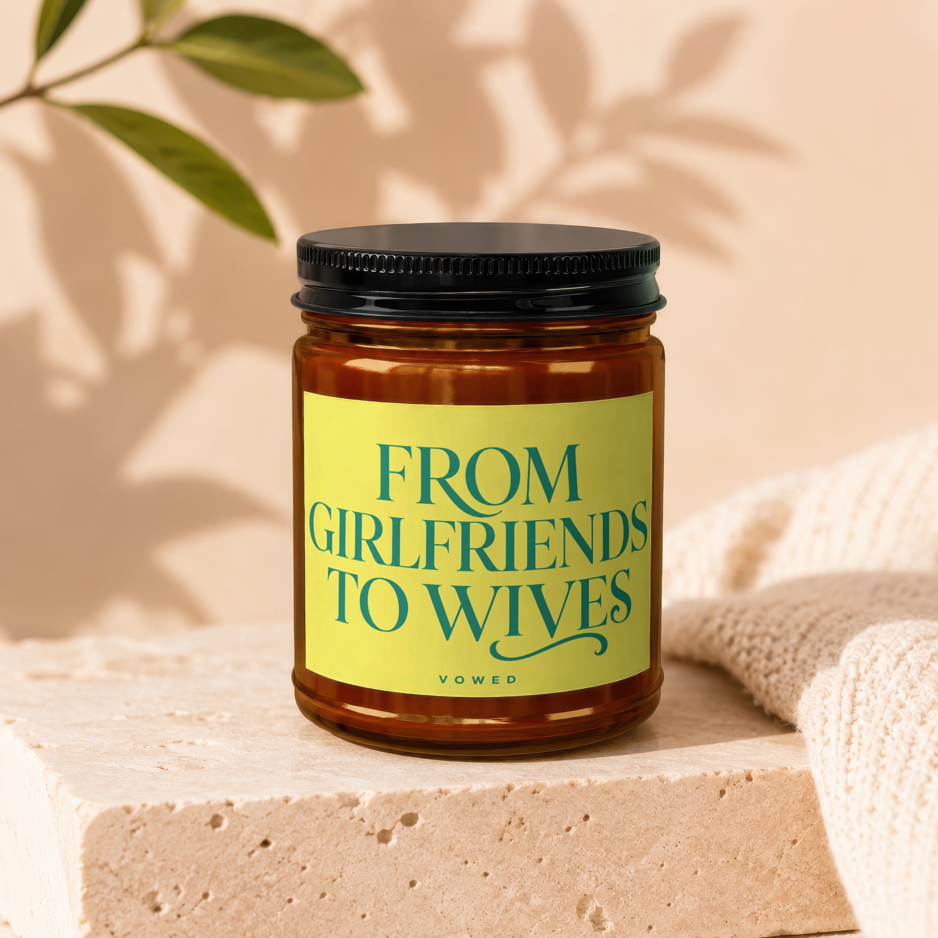 Amber jar candle with a yellow label reading "FROM GIRLFRIENDS TO WIVES VOWED".
