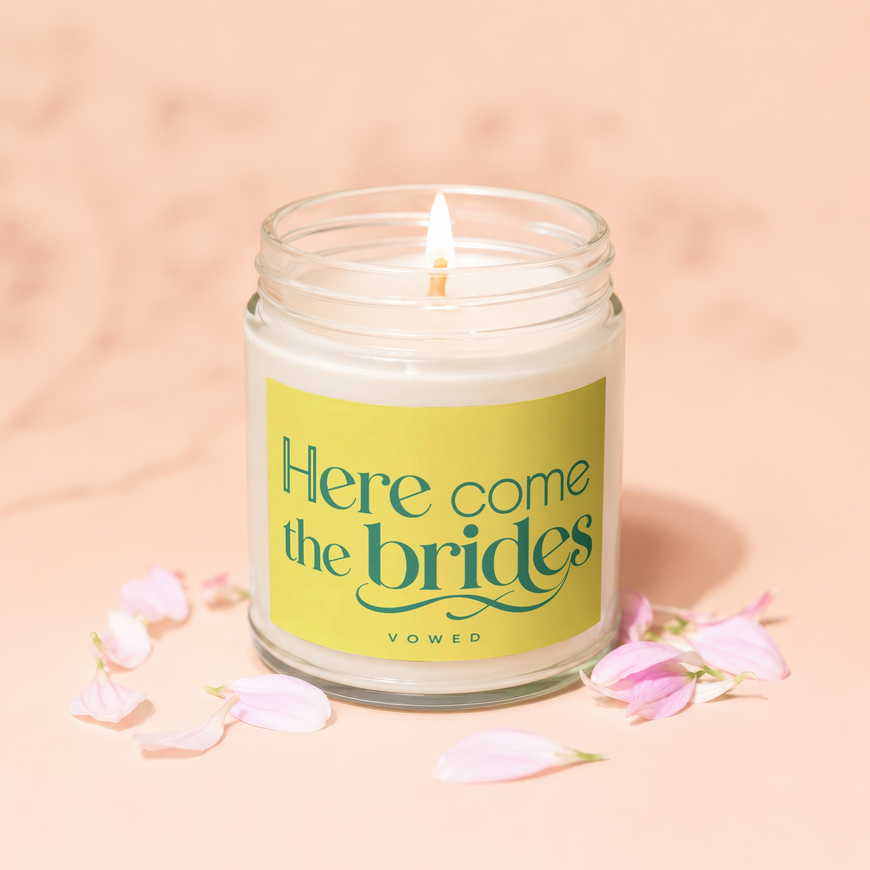 Jar candle with lit wick and "Here come the brides" text on yellow label.