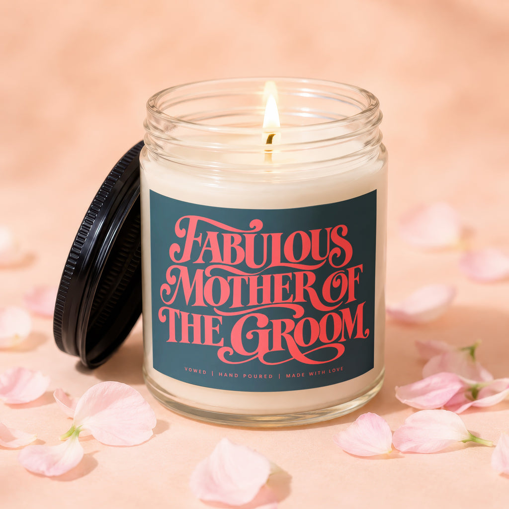 Candle labeled "Fabulous Mother of the Groom" with lit wick, surrounded by petals.