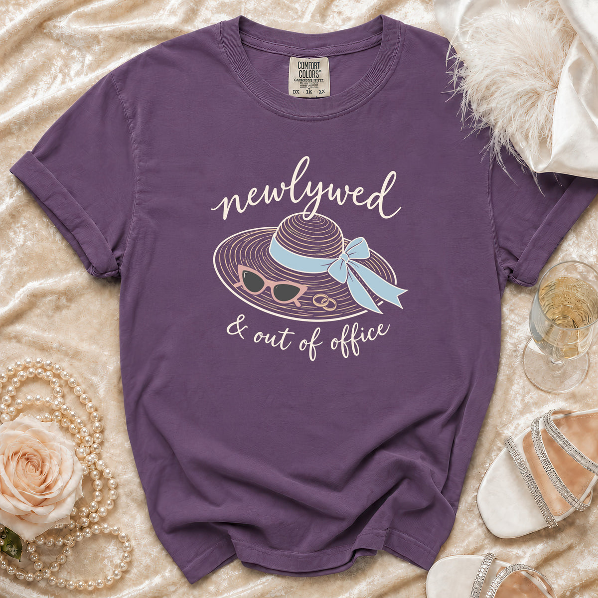 Purple t-shirt with "newlywed & out of office" text and beach accessories graphic.