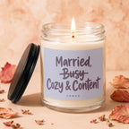 Burning candle in glass jar with "Married, Busy, Cozy & Content" text.