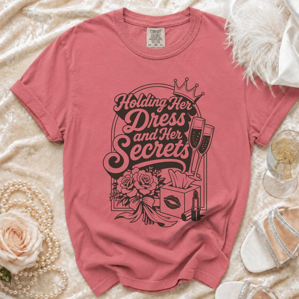 Pink t-shirt with "Holding Her Dress and Her Secrets" graphic and icons.