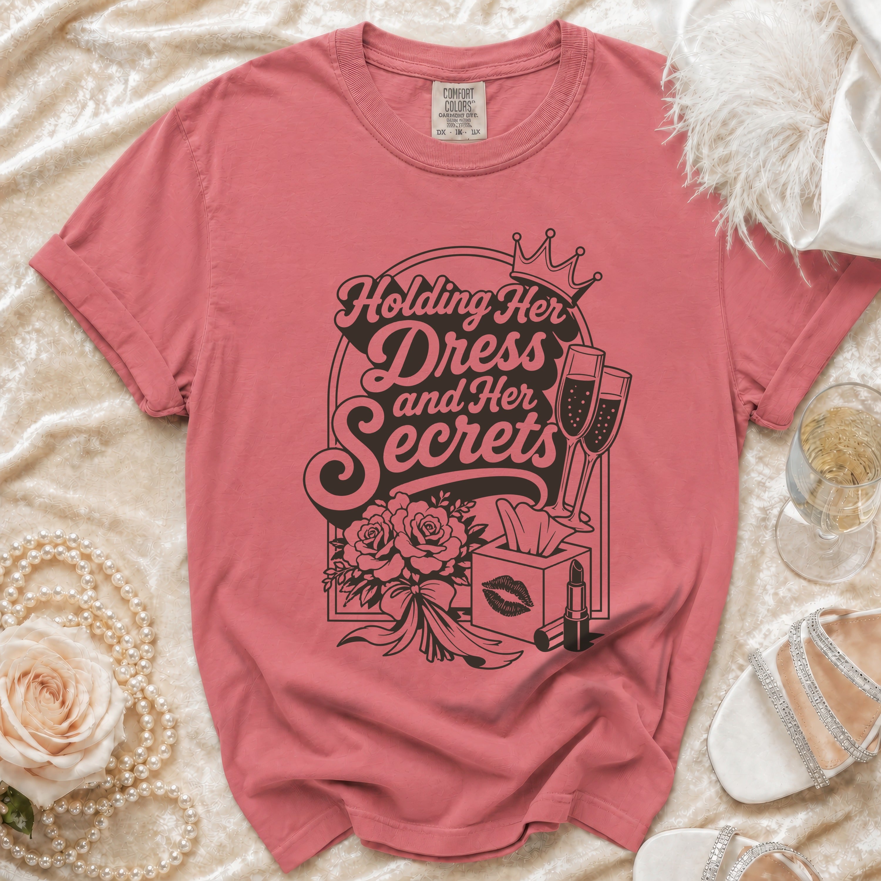 Pink t-shirt with "Holding Her Dress and Her Secrets" graphic and icons.