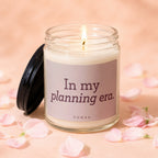 Glass jar candle with lit wick says "In my planning era."