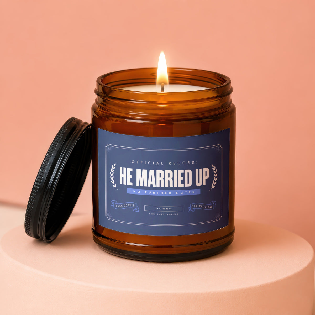 Amber jar candle with lit wick and "He Married Up" label.