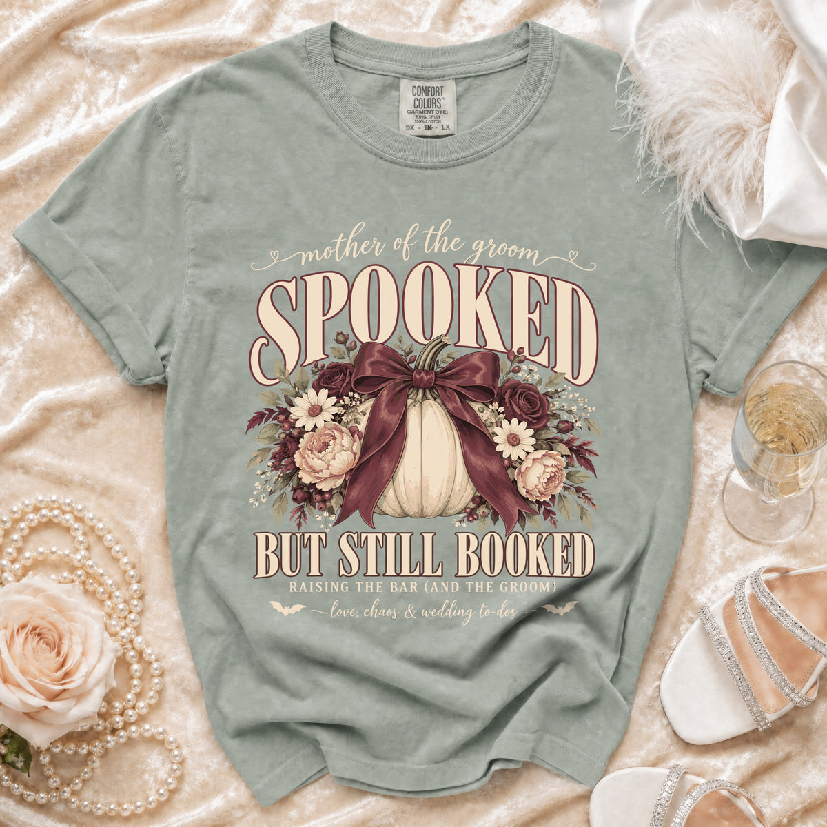 Green t-shirt with "Mother of the Groom Spooked But Still Booked" text and pumpkin graphic.