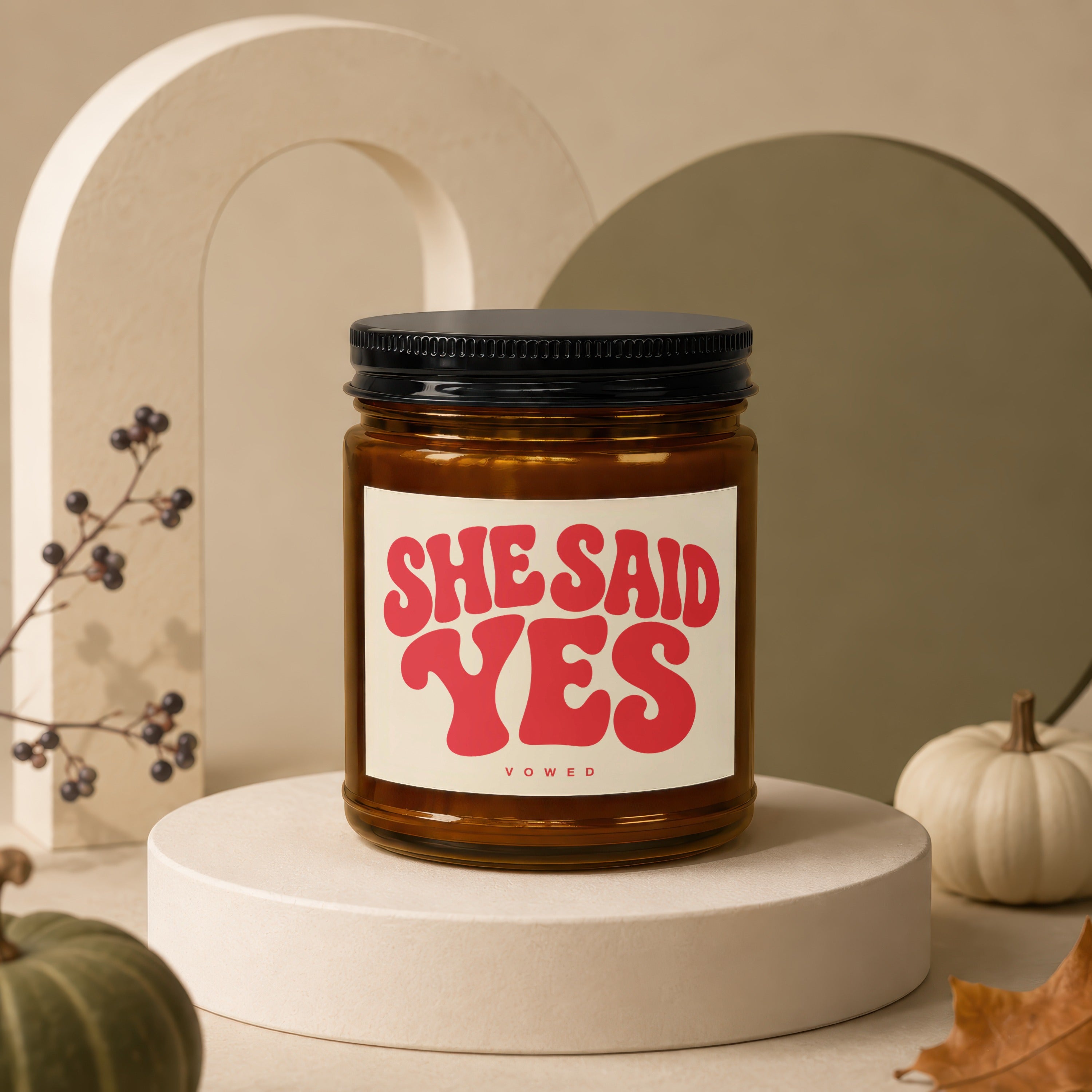 Amber jar candle with black lid and label reading "SHE SAID YES VOWED".