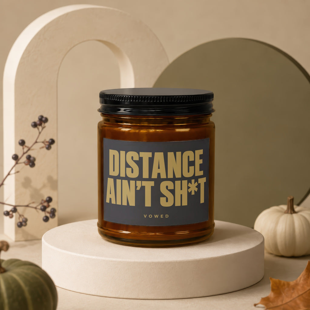 Amber jar candle with black lid, label reads "DISTANCE AIN'T SH*T VOWED".