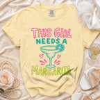Yellow t-shirt with "This Girl Needs A Margarita" graphic and margarita glass.