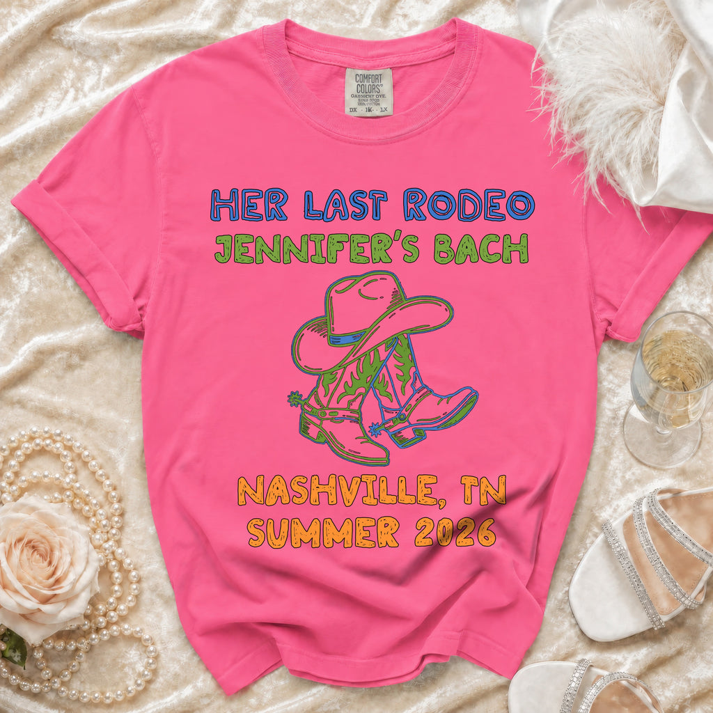 Pink t-shirt with "Her Last Rodeo" text, cowboy boots, and hat.