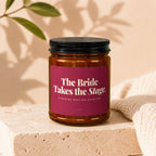 Amber candle jar with black lid, label reads "The Bride Takes the Stage."