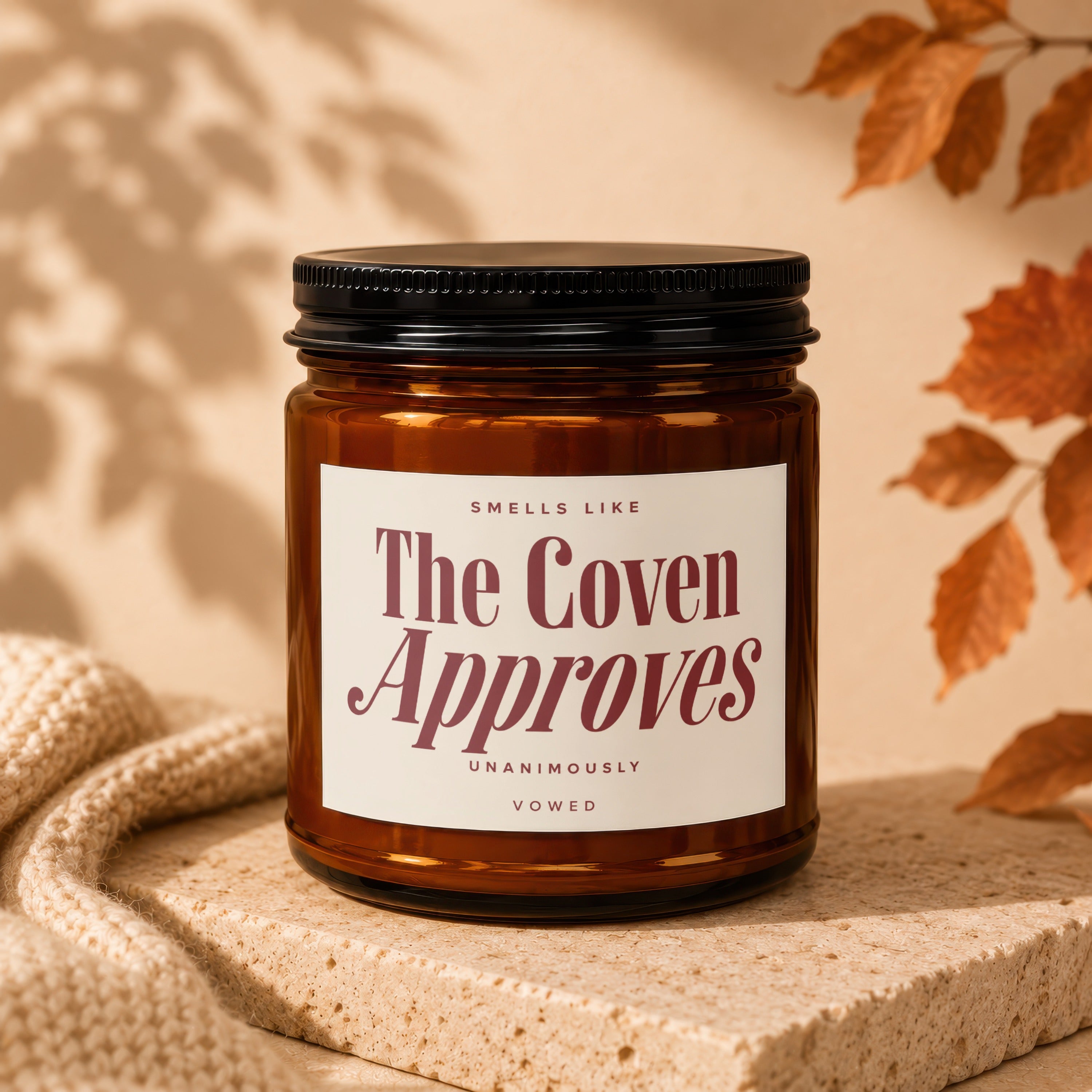 Amber jar candle with white label reading "The Coven Approves Unanimously Vowed".
