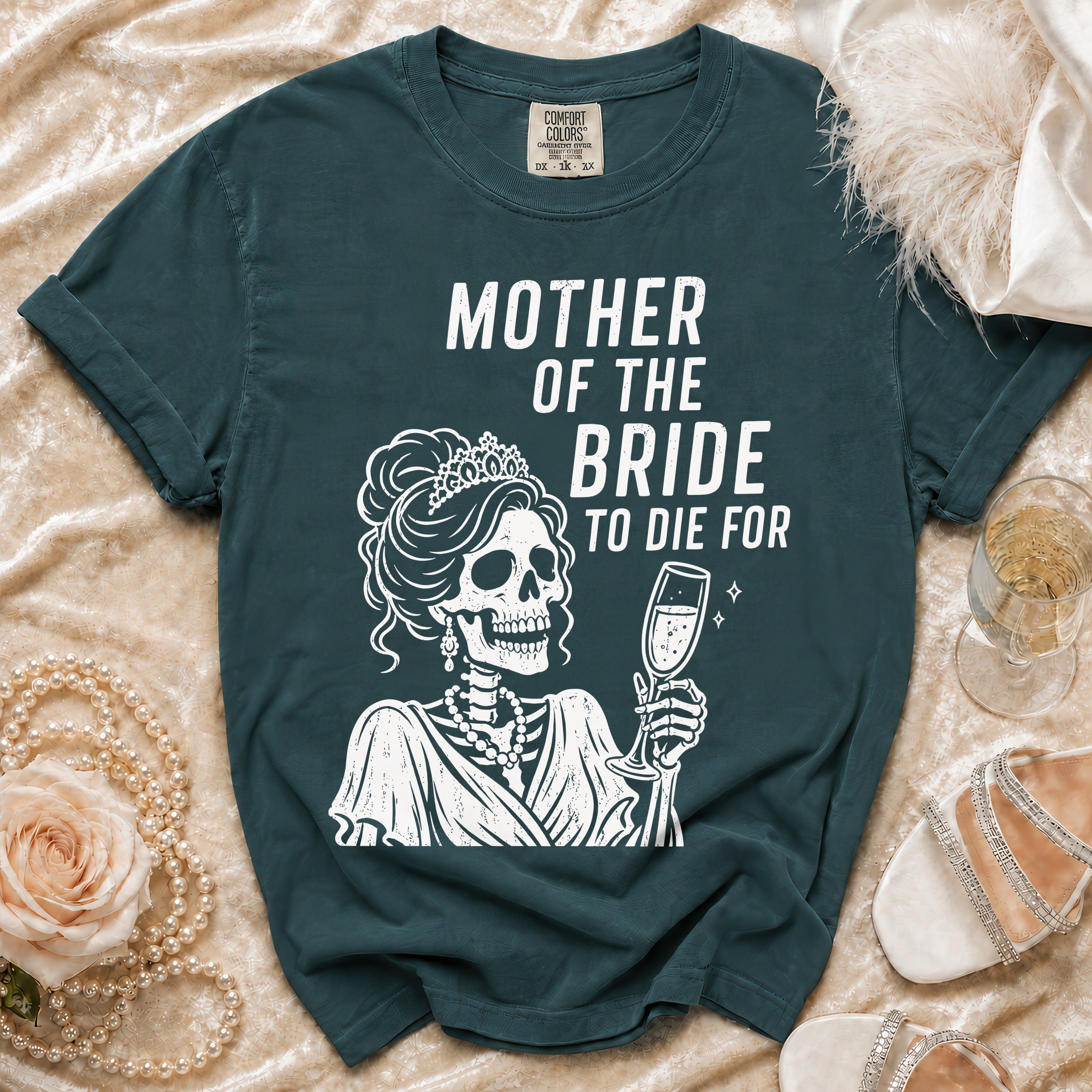 Dark teal t-shirt with a skeleton wearing a crown and holding champagne, reads "MOTHER OF THE BRIDE TO DIE FOR".