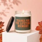 Lit candle with label "Thanks for the lifetime memory" on a white cube.