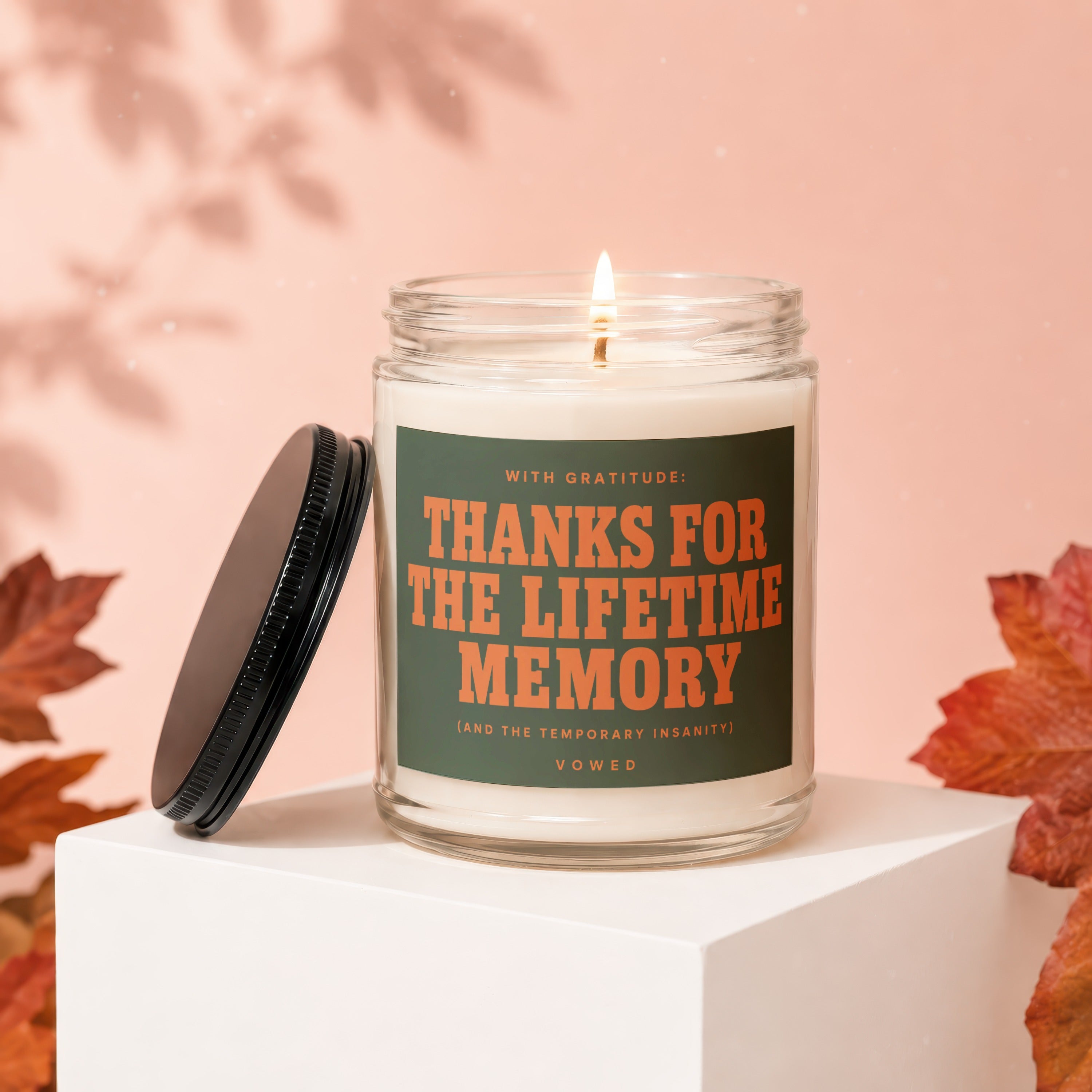 Lit candle with label "Thanks for the lifetime memory" on a white cube.