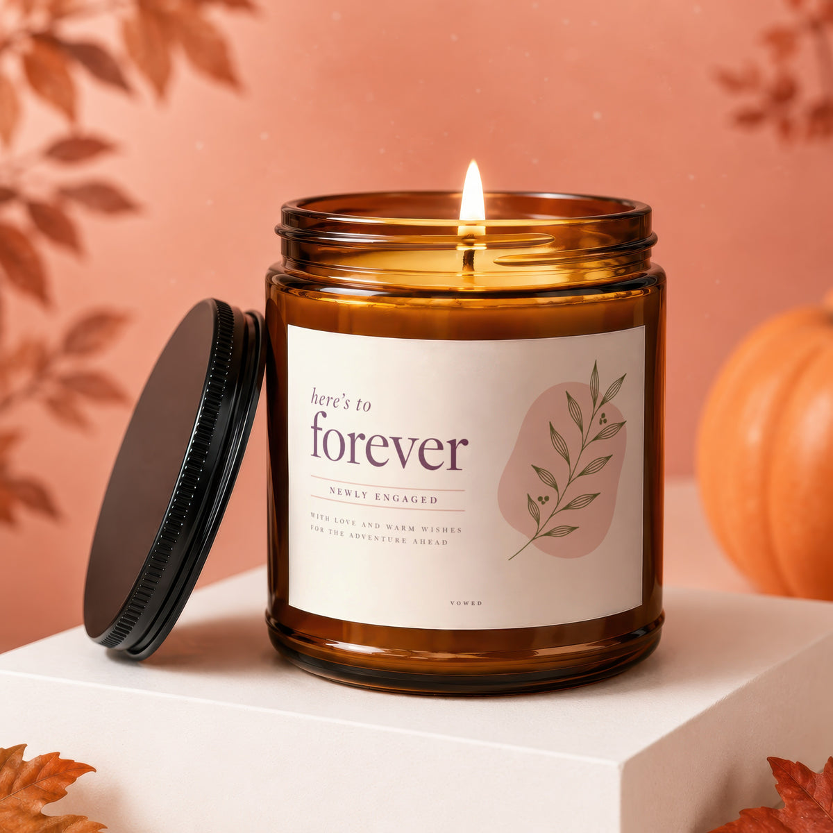 Amber jar candle with "here's to forever newly engaged" label, lit.
