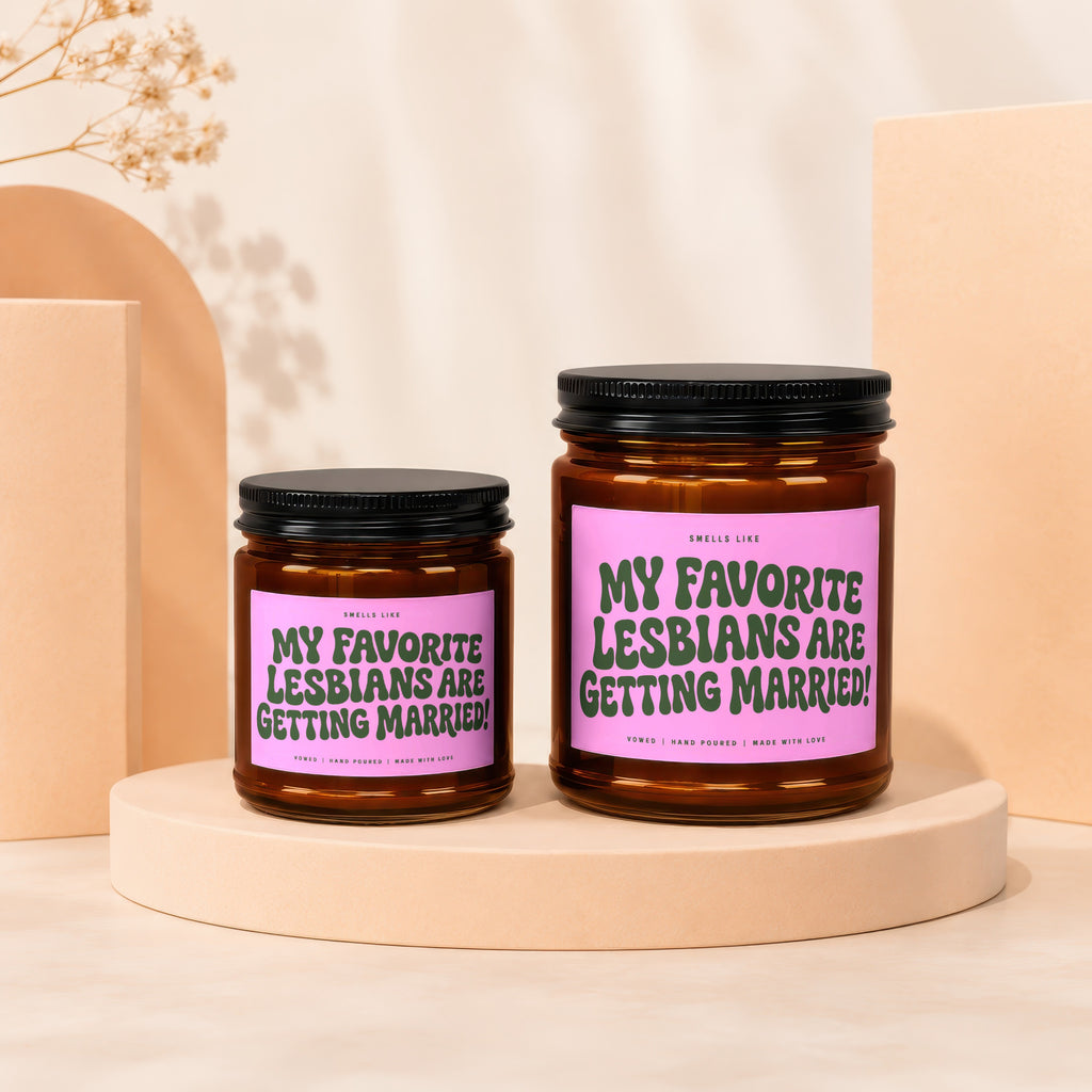 Two amber glass candles with pink labels reading "My Favorite Lesbians Are Getting Married!".