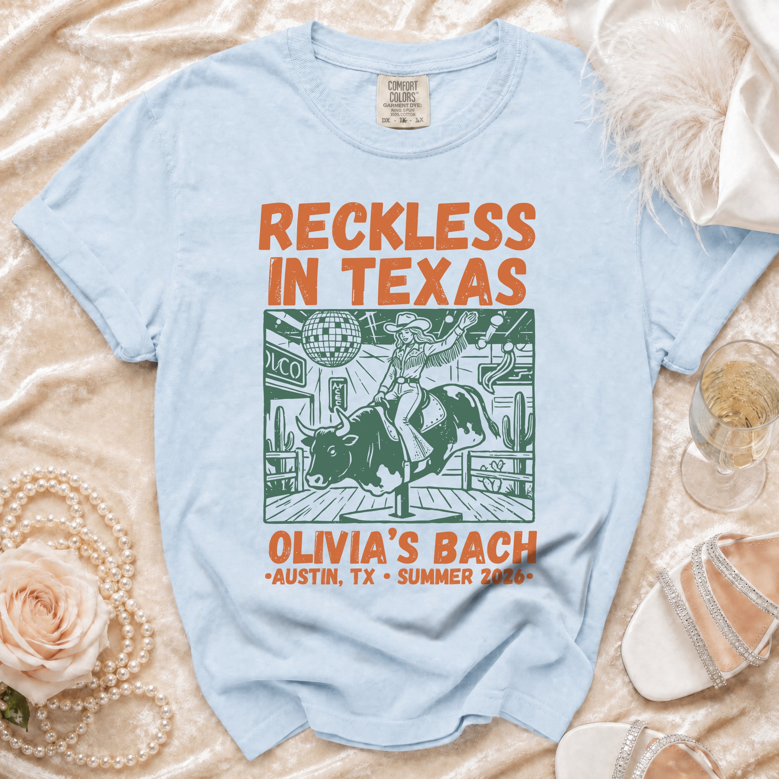 Light blue t-shirt with "Reckless in Texas" graphic and "Olivia's Bach Austin, TX Summer 2026".