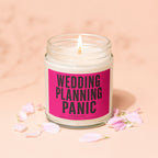 Candle with "Wedding Planning Panic Loading..." text on pink label, surrounded by pink petals.