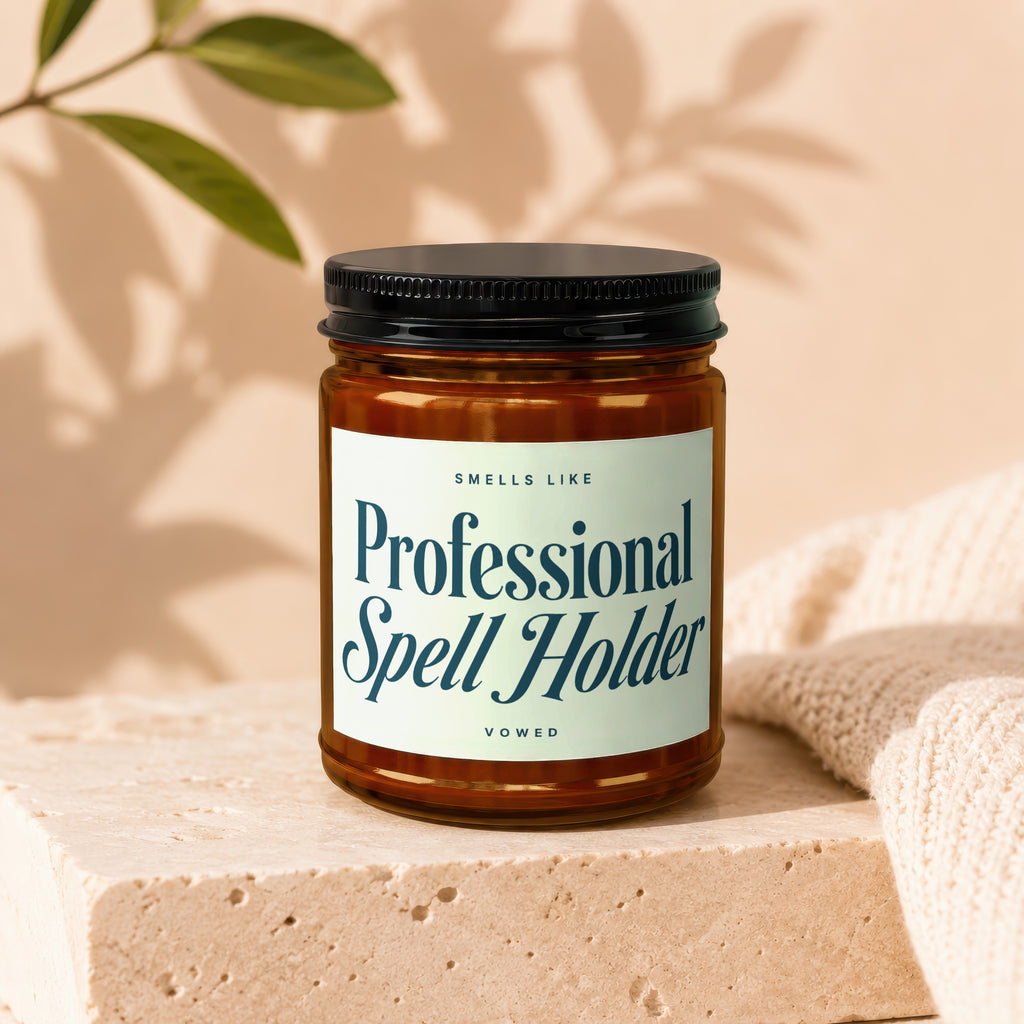 Amber jar candle labeled "Smells Like Professional Spell Holder" by Vowed.
