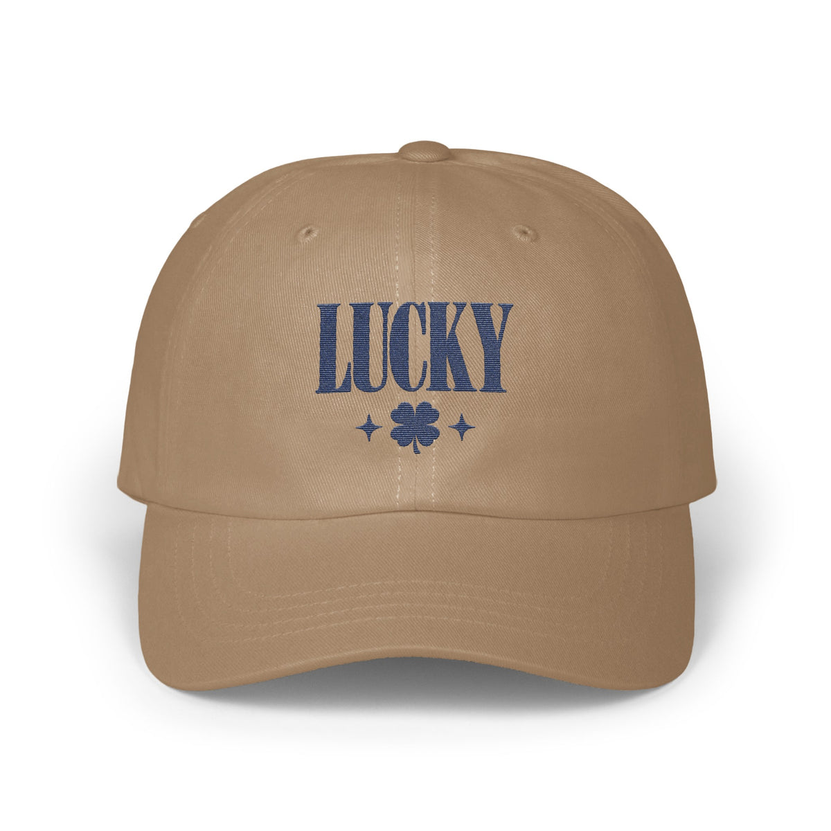 Tan baseball cap embroidered with the word LUCKY in blue, flanked by a four-leaf clover and two stars.