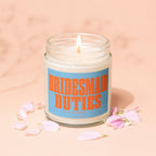 Candle with orange text "BRIDESMAID DUTIES (LOADING...)" on blue label, surrounded by petals.