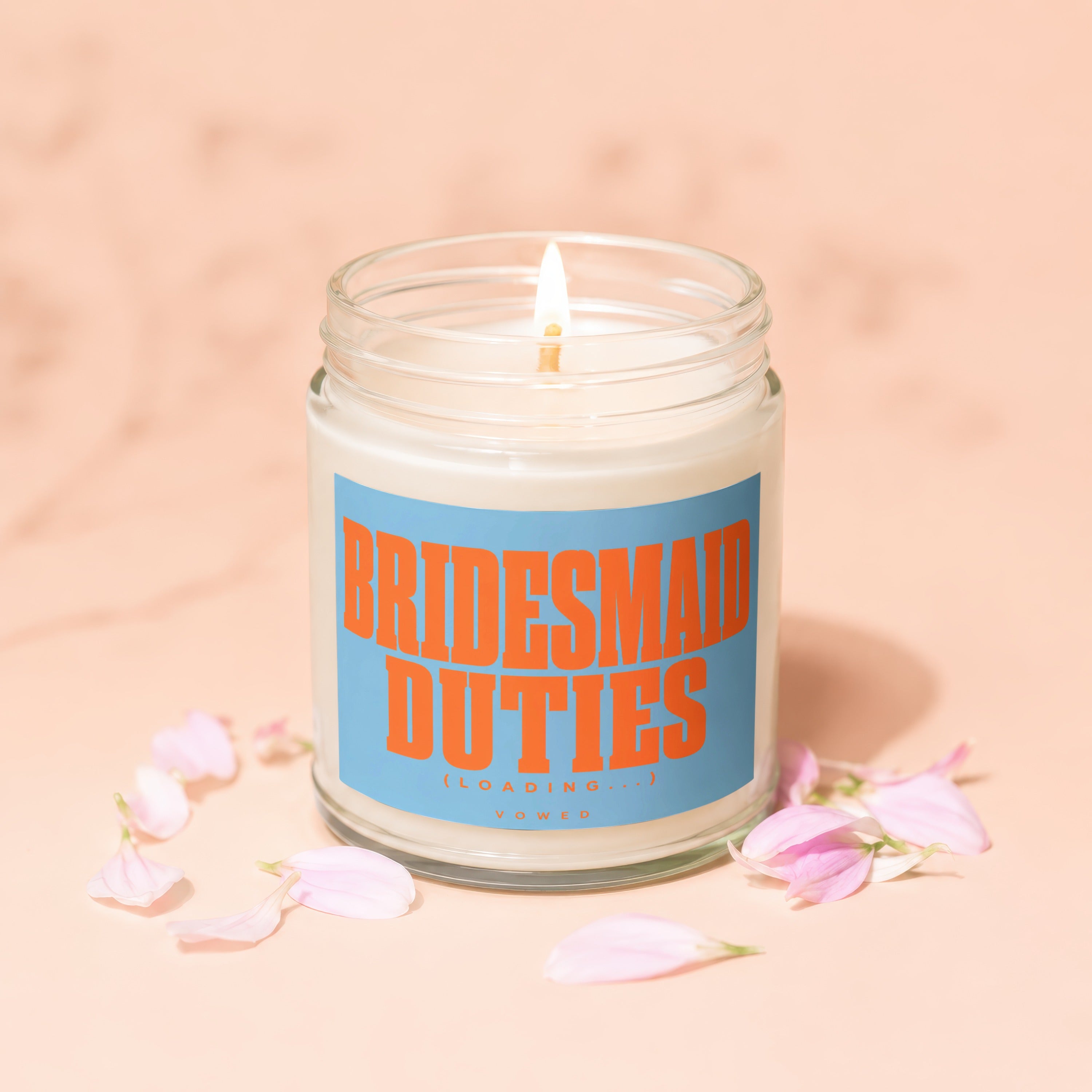 Candle with orange text "BRIDESMAID DUTIES (LOADING...)" on blue label, surrounded by petals.
