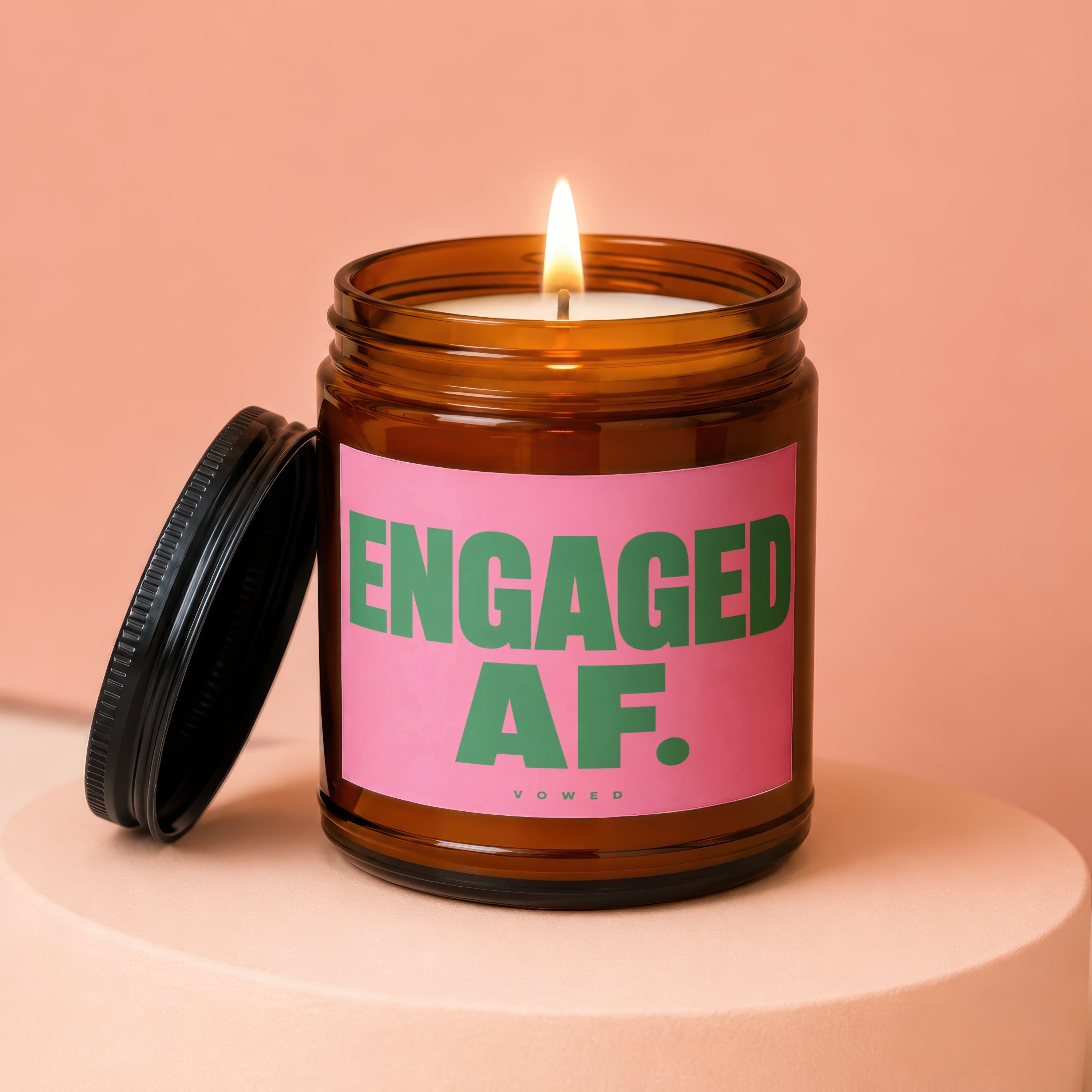 Candle with lid off, displaying "ENGAGED AF." text on pink label.