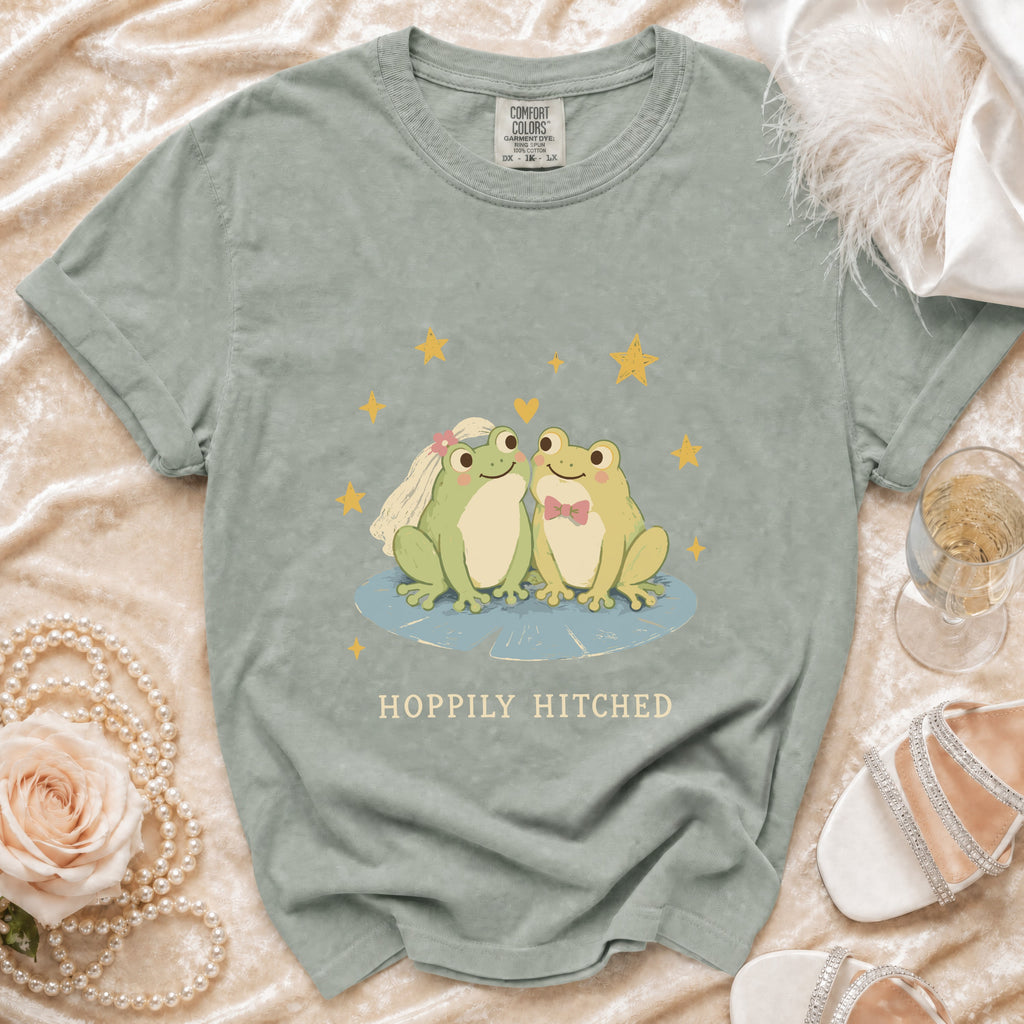 T-shirt with two cartoon frogs, wedding veil, bow tie, and "Happily Hitched" text.