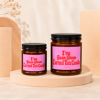 Two amber glass candles with pink labels that read "I've Been Given Earned This Candle."
