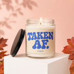 Scented candle with "TAKEN AF. VOWED" text on a pale background.