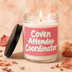 Candle with lit wick, the label reads "Coven Attendee Coordinator VOWED."