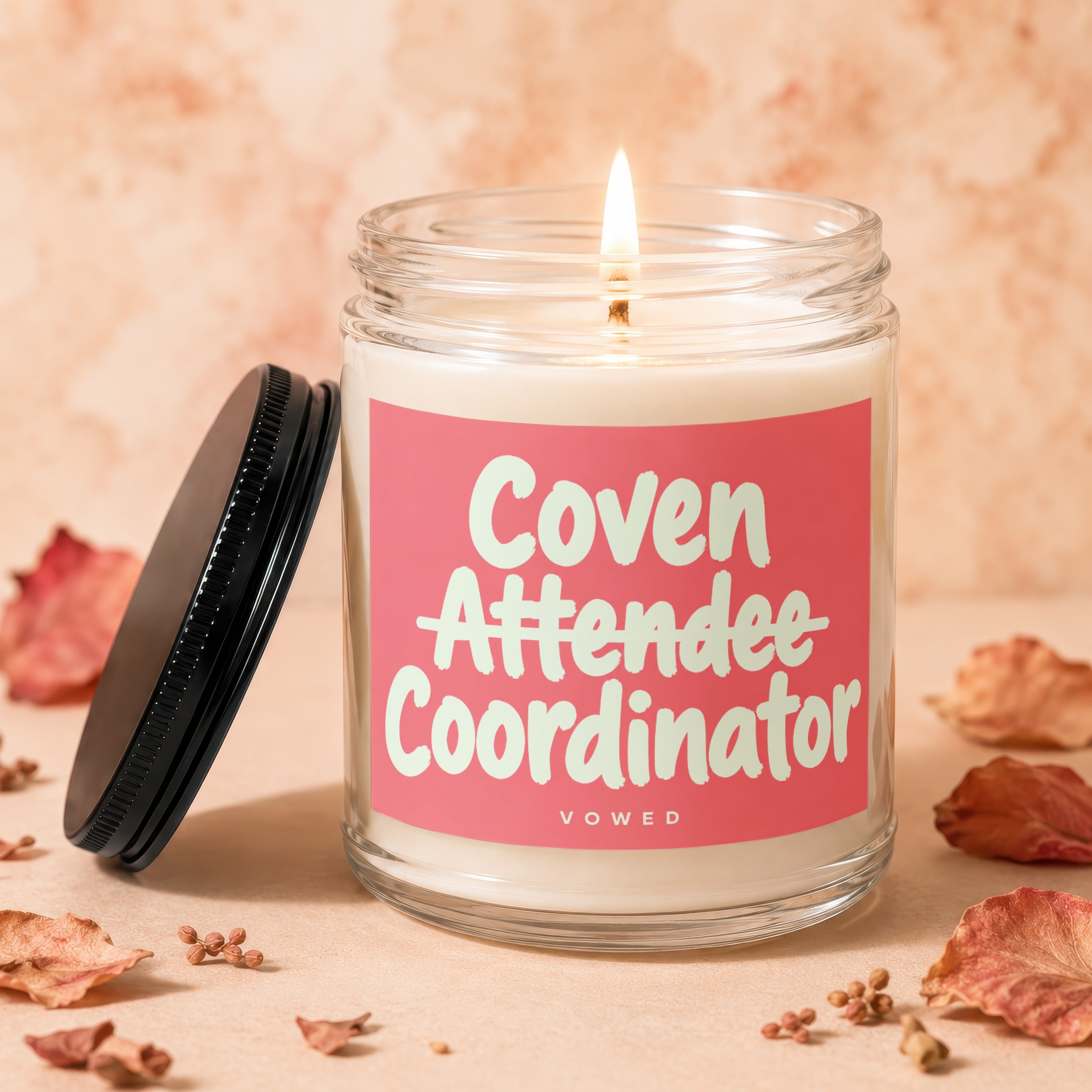 Candle with lit wick, the label reads "Coven Attendee Coordinator VOWED."