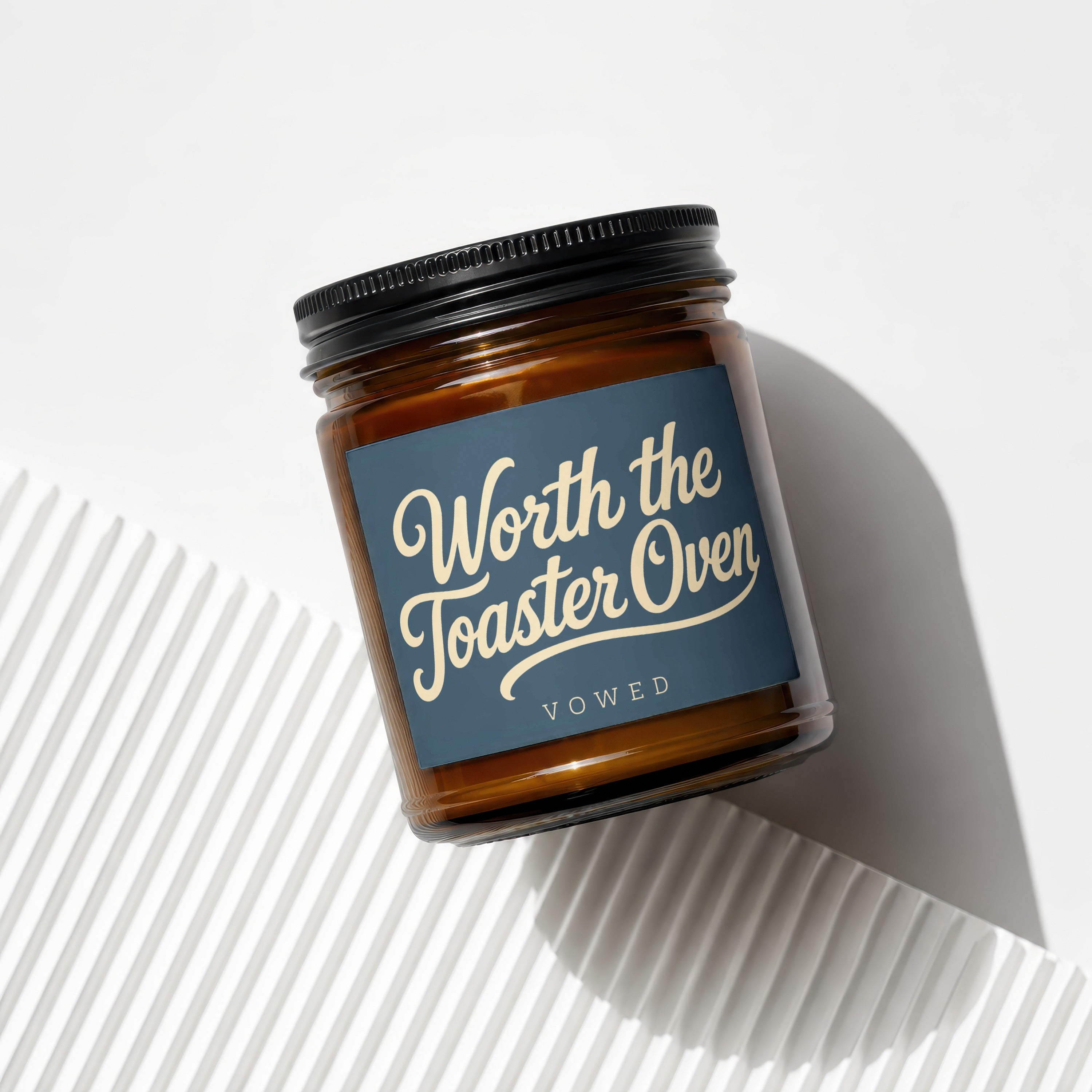 Amber glass candle labeled "Worth the Toaster Oven" and "vowed".