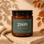 Amber glass candle with a dark green label showing "Established 2009 Ruth + Caleb Still Going Strong".