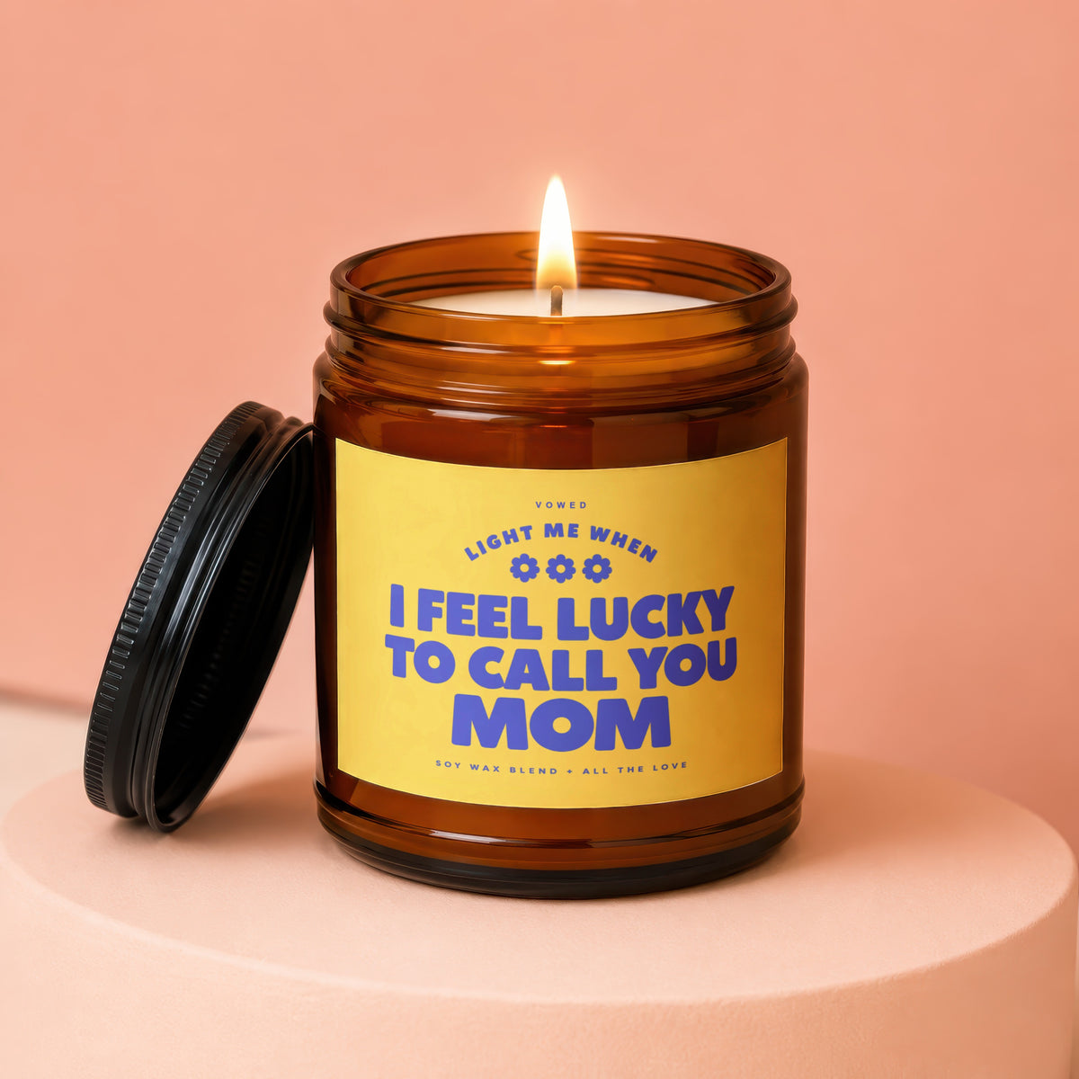 Amber jar candle with lit flame and yellow label reading "I feel lucky to call you Mom."