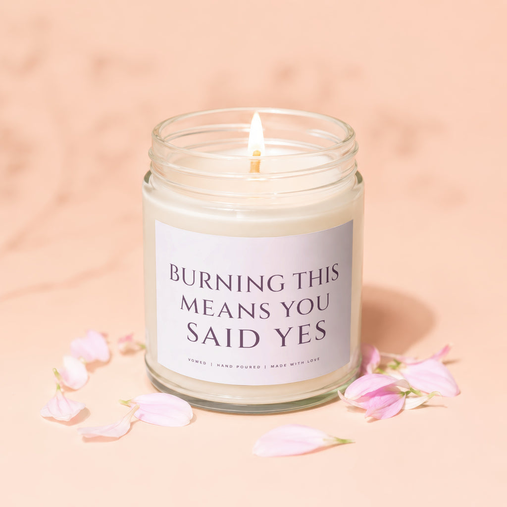 Candle with text "BURNING THIS MEANS YOU SAID YES" and pink petals.